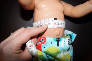Für den Hosenbund müssen wir den Bauchumfang der Puppe messen.
